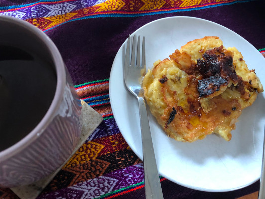another plate of french toast, on a colorful embroidered tablecloth, with a cup of tea next to it